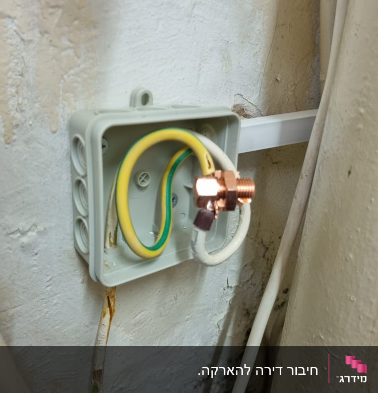 תיבת חיבורים עם חוטי חשמל חשופים על קיר